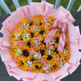 Bouquet of yellow sunflowers and pink roses wrapped in pink paper