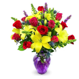 Bouquet of red roses and yellow lilies in a purple glass vase