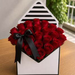 Red roses arranged in a black-and-white striped gift box with a black ribbon