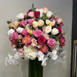 Large bouquet of pink, white, and peach flowers in a tall green vase