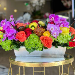 Rectangular flower arrangement with orchids, roses, and hydrangeas in a white container
