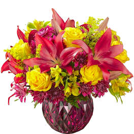 Bright bouquet of pink lilies and yellow roses in a faceted vase