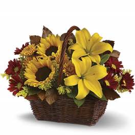 Basket arrangement with yellow lilies, sunflowers, and red daisies