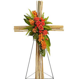 Floral cross on an easel with orange roses and greenery