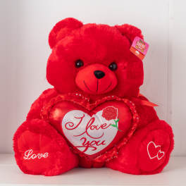 Large red teddy bear holding a red and white heart with I love you text