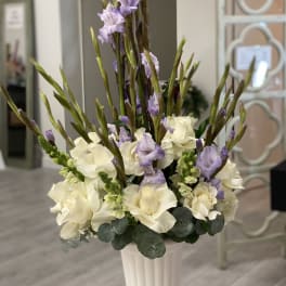 Tall white and lavender floral arrangement in a white vase