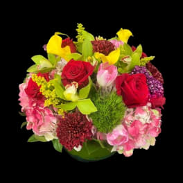 Mixed bouquet with red roses, yellow calla lilies, and pink flowers in a vase