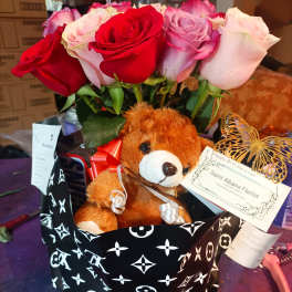 Bouquet of red, pink, and lavender roses with a teddy bear in a gift wrap