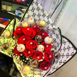 Bouquet of red roses with small wrapped chocolates in patterned paper