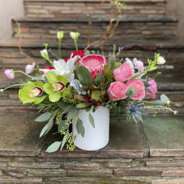 Pink roses and orchids arranged in a white textured vase