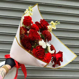 Bouquet of red roses and red carnations wrapped in white paper