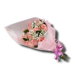 Bouquet of light pink roses with white filler flowers wrapped in pink paper and ribbon