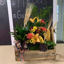 Autumn floral arrangement in a wooden crate with lilies and sunflowers