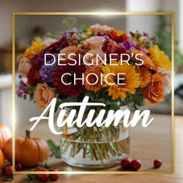 Autumn bouquet of mixed flowers in a glass vase with pumpkins nearby