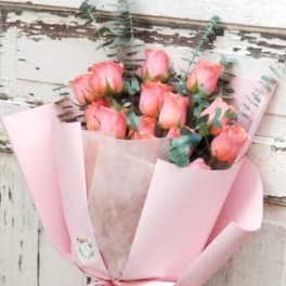 Pink rose bouquet wrapped in pastel pink paper with a ribbon