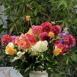 Bright mixed bouquet in a cream vase with pink, yellow, white, and purple blooms