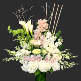 Tall white and blush floral arrangement in a green vase