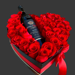 Heart-shaped box of red roses with a wine bottle in the center