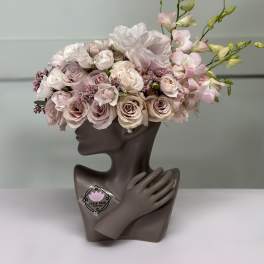 Pink and white floral arrangement in a sculptural bust vase