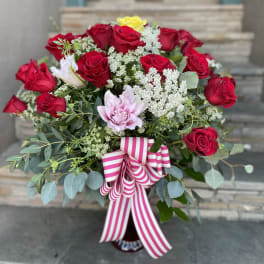 Bouquet of red roses with pink and yellow blooms and a striped ribbon