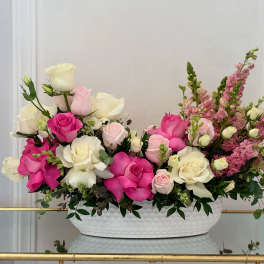 Pink and white roses with pink snapdragons in a white oval vase