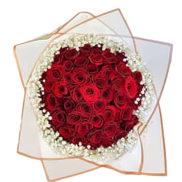 Round bouquet of red roses with white baby's breath in clear wrap