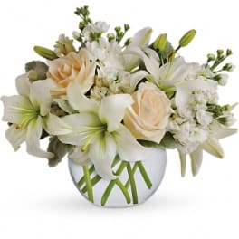 White lilies and pale roses arranged in a round glass vase