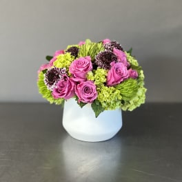 Pink roses and green flowers arranged in a white vase