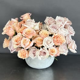 Arrangement of pale pink and peach roses in a light blue vase