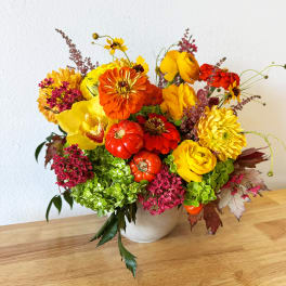 Bright mixed bouquet in a white vase with yellow, orange, and red flowers