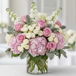 Pink and white roses with hydrangeas in a clear glass vase