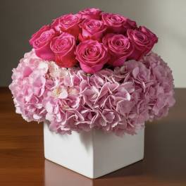 Pink roses and hydrangeas arranged in a white square vase