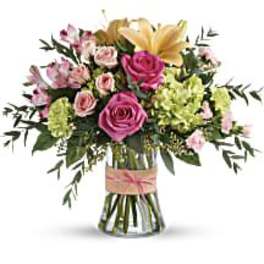 Bouquet of pink roses, lilies, and green hydrangeas in a glass vase