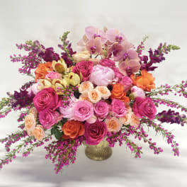 Large bouquet of pink, peach, and purple flowers in a gold vase