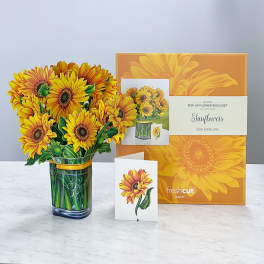 Pop-up bouquet of yellow sunflowers in a glass vase with an orange gift box