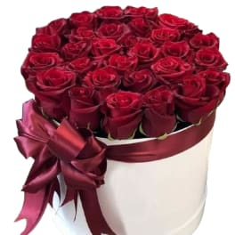 Round box of red roses with a burgundy ribbon bow