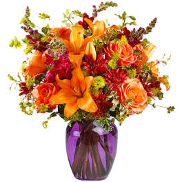 Orange lilies and roses in a purple glass vase