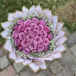 Round bouquet of pink roses with white baby's breath and pale ribbon wrap