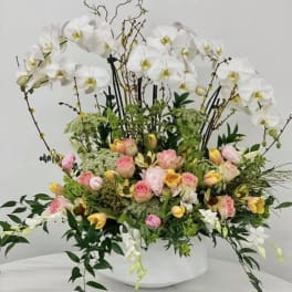 Large floral arrangement with white orchids and pink roses in a white vase