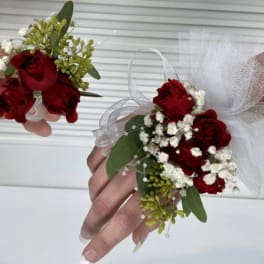 Red rose corsages with white baby's breath and tulle ribbon