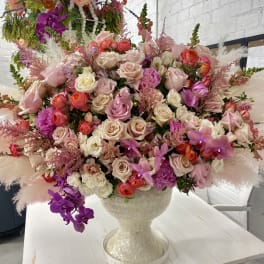 Large mixed bouquet of pink, cream, and purple flowers in a white vase