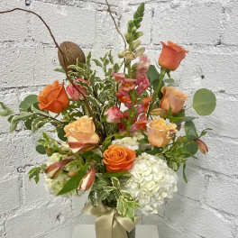 Orange and peach roses with white hydrangeas in a glass vase