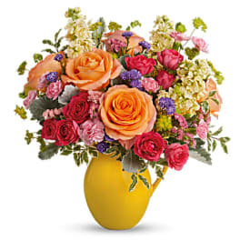 Mixed bouquet of orange and pink roses in a yellow vase