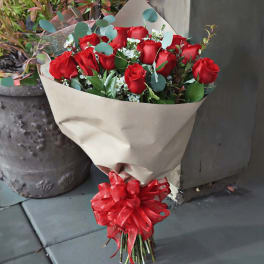Bouquet of red roses wrapped in beige paper with a red ribbon