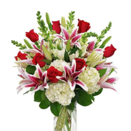 Bouquet of red roses, pink lilies, and white hydrangeas in a glass vase