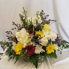 Mixed bouquet in a low rectangular container with white, yellow, and purple flowers