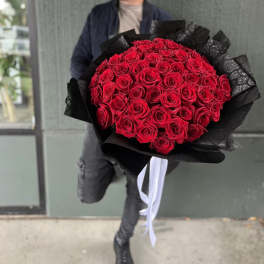 Large bouquet of red roses wrapped in black paper with white ribbon