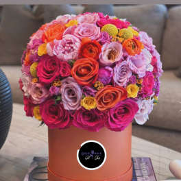 Round bouquet of pink, orange, and yellow roses in a peach hat box