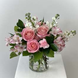 Pink roses and white flowers arranged in a clear glass vase