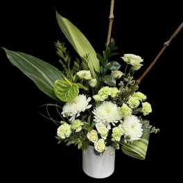 White and pale green floral arrangement in a white vase